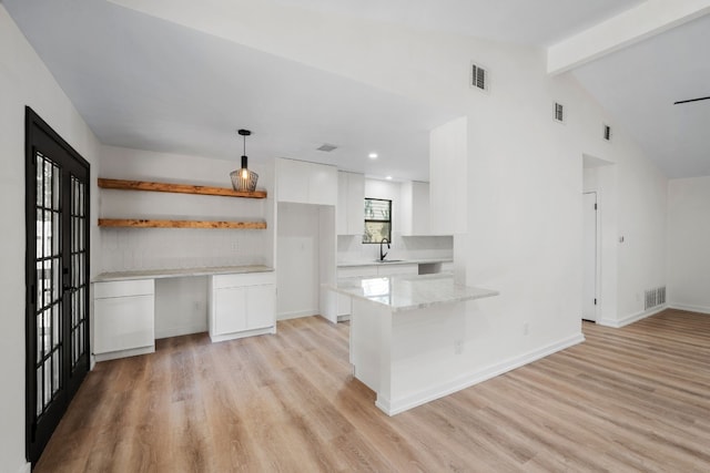 kitchen with white cabinets, vaulted ceiling with beams, kitchen peninsula, and light hardwood / wood-style flooring