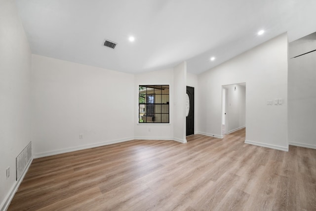 empty room with lofted ceiling and light hardwood / wood-style floors