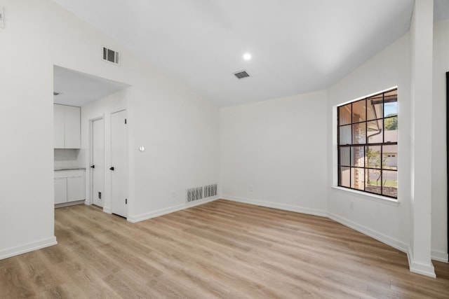 empty room featuring light wood-type flooring and vaulted ceiling