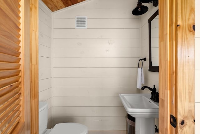 bathroom featuring wood walls, sink, and toilet