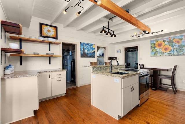 kitchen with stainless steel electric range, white cabinets, light hardwood / wood-style flooring, an island with sink, and beam ceiling