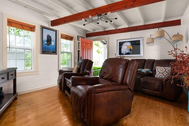 home theater room with beamed ceiling, plenty of natural light, and light hardwood / wood-style flooring