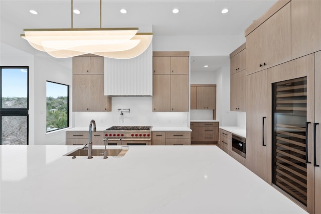 kitchen featuring built in microwave, sink, wine cooler, range with two ovens, and light brown cabinets