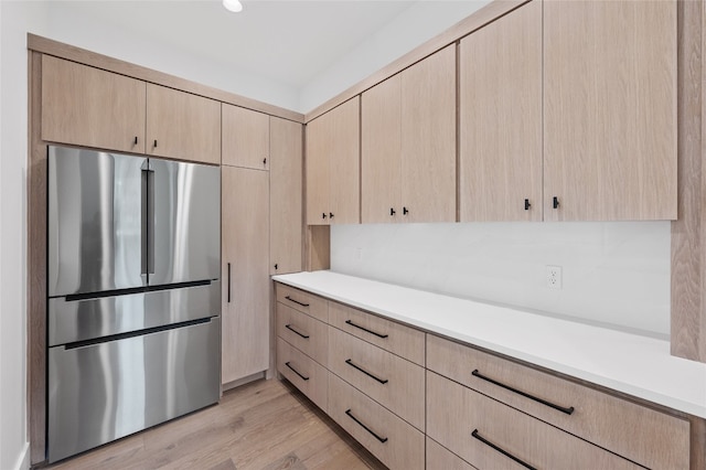 kitchen with light brown cabinets, stainless steel fridge, and light hardwood / wood-style flooring