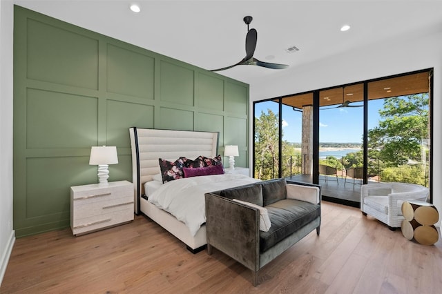 bedroom featuring access to outside, a water view, light hardwood / wood-style flooring, and ceiling fan