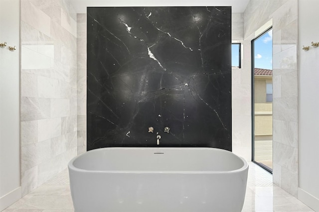 bathroom featuring tile patterned flooring, a washtub, and tile walls