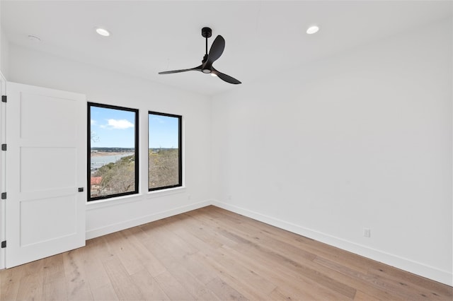 empty room featuring ceiling fan, light hardwood / wood-style floors, and a water view