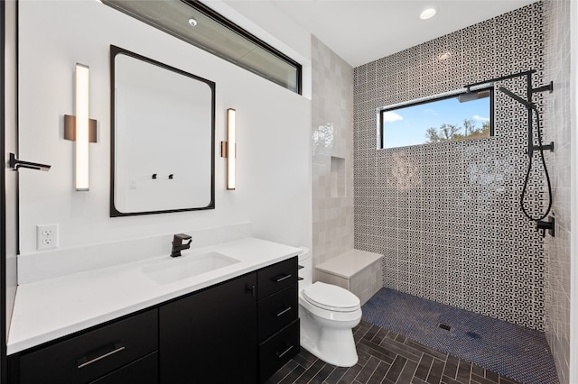 bathroom featuring vanity, a tile shower, and toilet