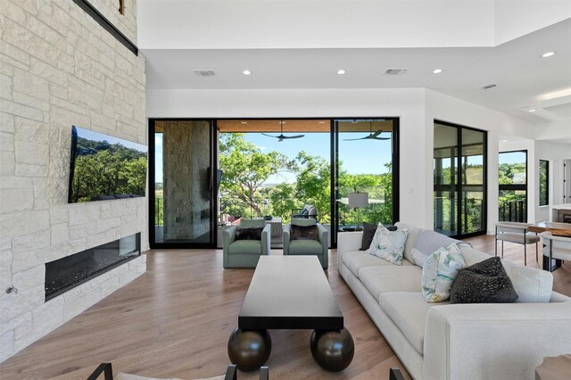 living room with a fireplace, light hardwood / wood-style floors, and ceiling fan