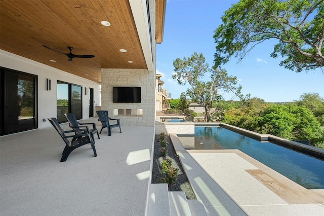 view of swimming pool with ceiling fan, a patio, and an outdoor stone fireplace