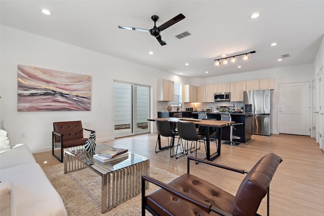 living room featuring rail lighting, ceiling fan, and light hardwood / wood-style floors