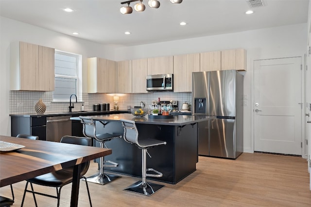 kitchen featuring a kitchen bar, a center island, stainless steel appliances, and light hardwood / wood-style flooring