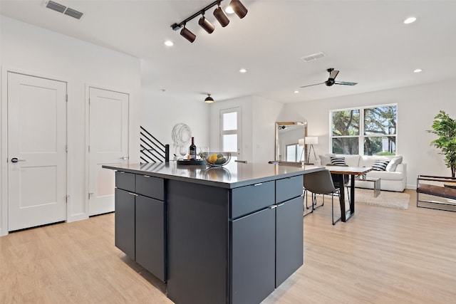 kitchen with light wood-type flooring, ceiling fan, and a center island