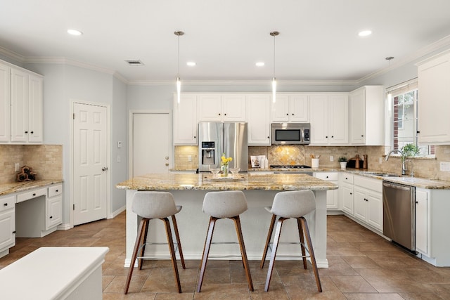 kitchen featuring hanging light fixtures, stainless steel appliances, a center island with sink, and sink