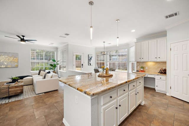 kitchen with white cabinets, backsplash, decorative light fixtures, and a kitchen island