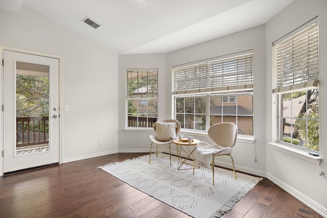 living area with lofted ceiling, a wealth of natural light, and dark hardwood / wood-style floors