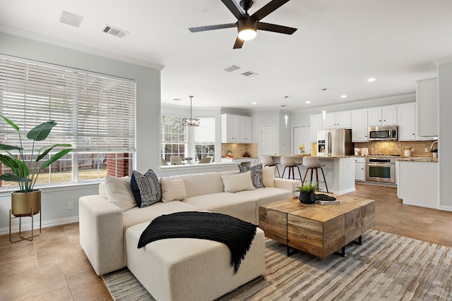 living room featuring crown molding and ceiling fan with notable chandelier