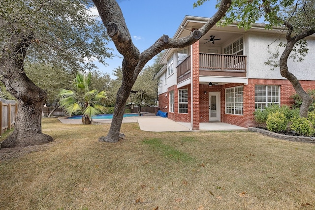 back of house featuring a fenced in pool, ceiling fan, a balcony, a yard, and a patio