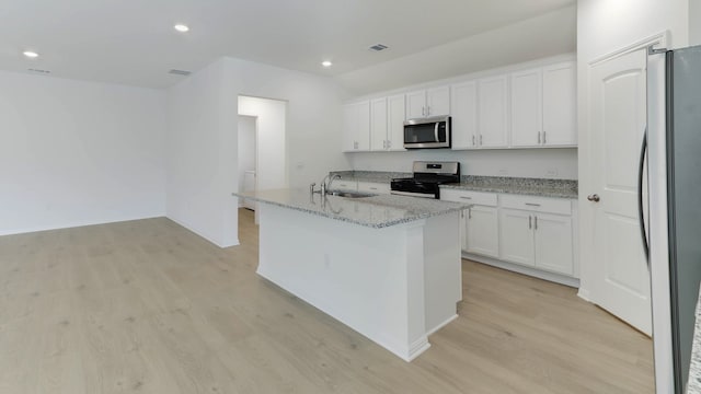 kitchen with white cabinets, appliances with stainless steel finishes, light wood-type flooring, and a kitchen island with sink