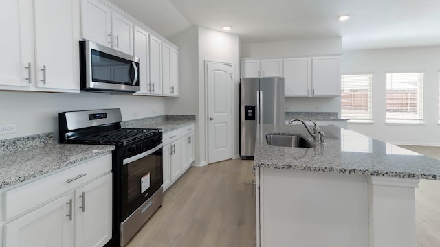 kitchen with light hardwood / wood-style floors, an island with sink, white cabinets, stainless steel appliances, and sink