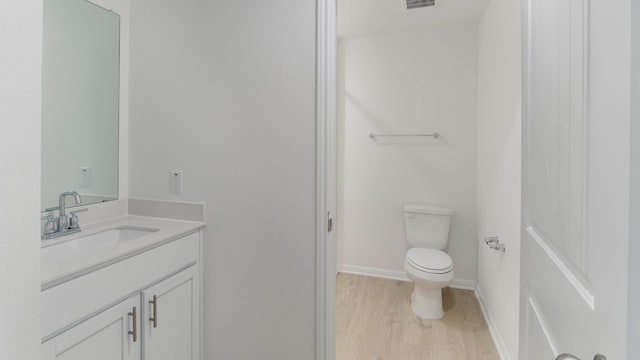 bathroom featuring vanity, toilet, and hardwood / wood-style flooring