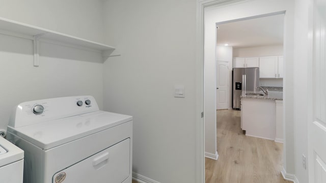 washroom with washing machine and dryer and light hardwood / wood-style floors