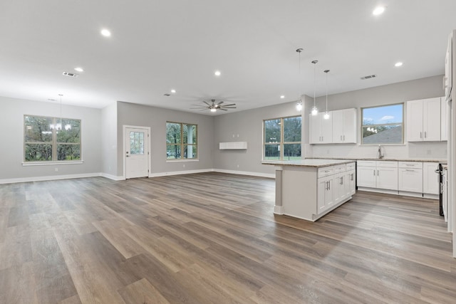 kitchen featuring a kitchen island, ceiling fan, white cabinetry, wood-type flooring, and decorative light fixtures