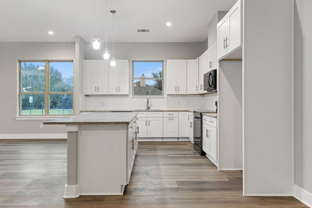 kitchen with white cabinetry, black appliances, hanging light fixtures, and a kitchen island