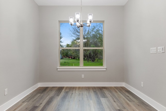 unfurnished dining area featuring hardwood / wood-style floors and a chandelier