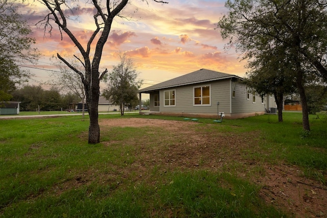 property exterior at dusk with central AC and a lawn