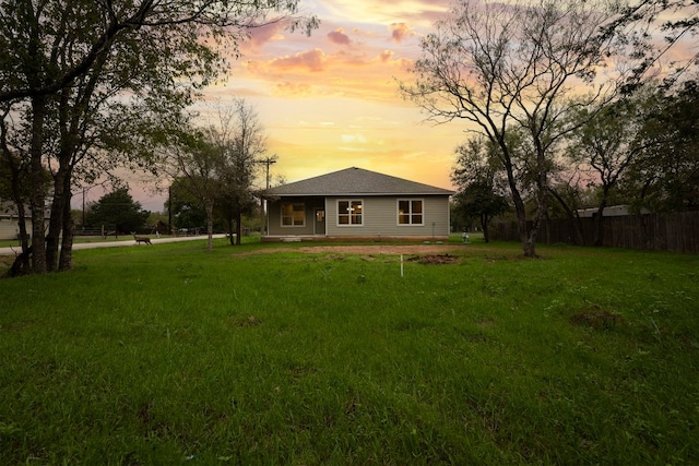 back house at dusk featuring a yard