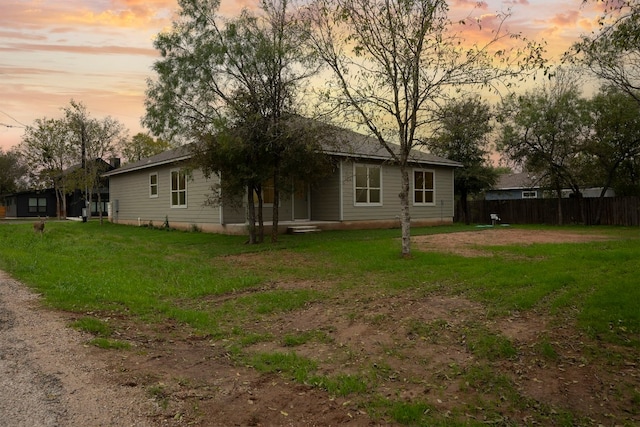 back house at dusk with a lawn