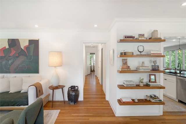 hallway featuring light hardwood / wood-style flooring, ornamental molding, and sink