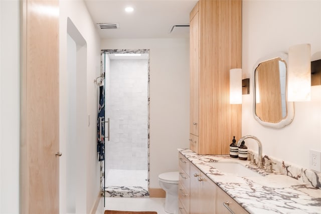 bathroom featuring a tile shower, vanity, toilet, and tile patterned floors