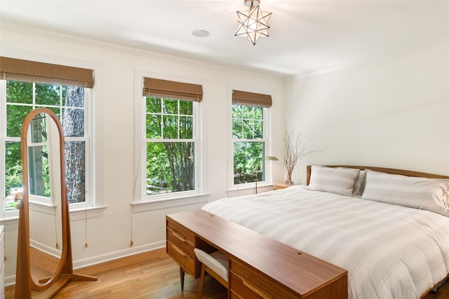 bedroom with light wood-type flooring, crown molding, and multiple windows