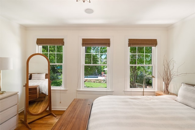 bedroom with ornamental molding, multiple windows, and hardwood / wood-style flooring