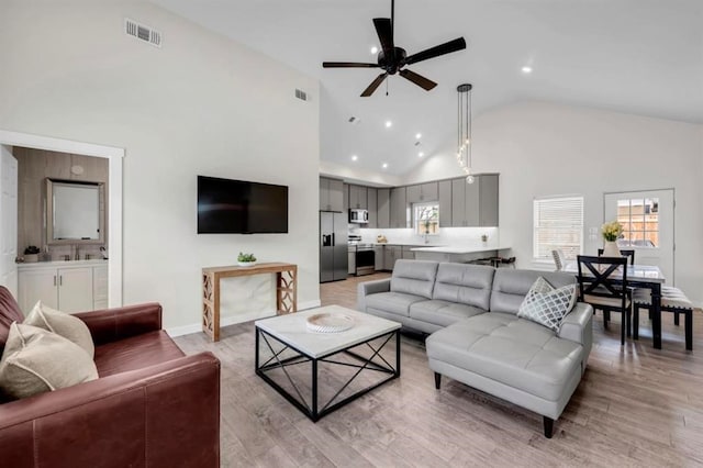 living room with light wood-type flooring, high vaulted ceiling, and ceiling fan