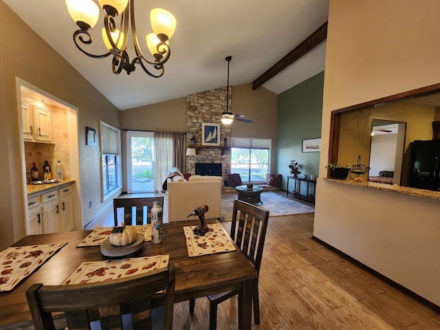 dining space with light hardwood / wood-style flooring, ceiling fan with notable chandelier, a fireplace, and a healthy amount of sunlight