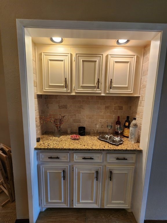 kitchen with light stone counters, white cabinets, and decorative backsplash