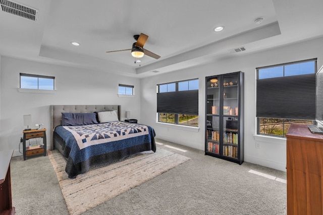 bedroom with carpet flooring, ceiling fan, and a raised ceiling