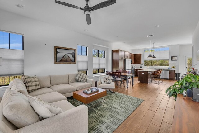 living room with plenty of natural light, ceiling fan, and light hardwood / wood-style flooring