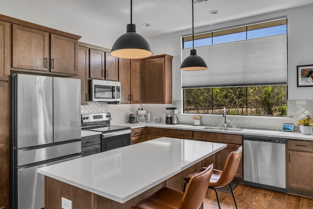 kitchen with backsplash, decorative light fixtures, stainless steel appliances, a center island, and sink