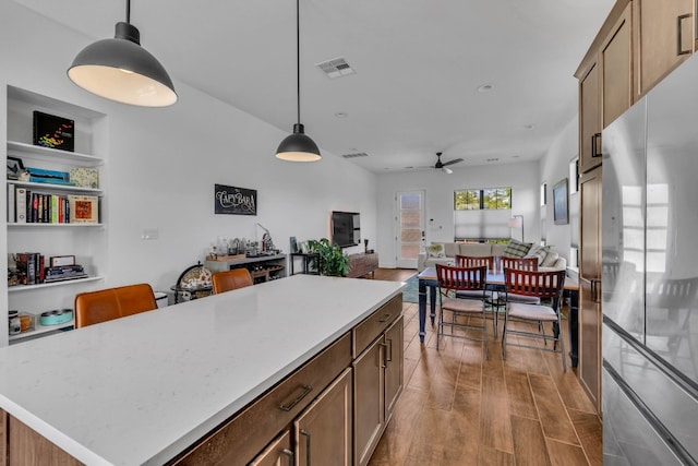 kitchen with hanging light fixtures, light hardwood / wood-style floors, stainless steel fridge, ceiling fan, and a kitchen island