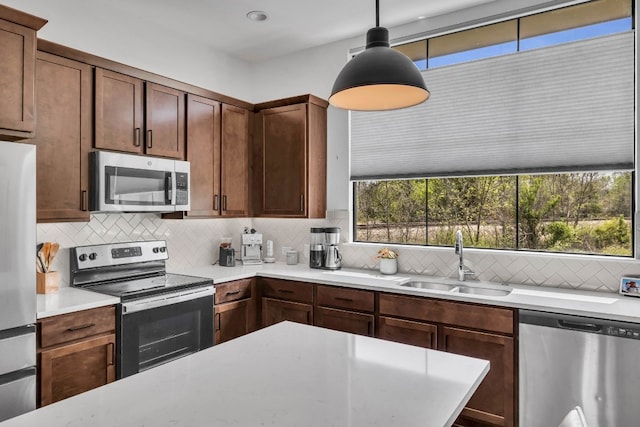 kitchen featuring backsplash, decorative light fixtures, stainless steel appliances, and sink