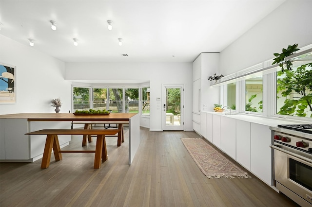 kitchen with wood-type flooring, white cabinetry, and luxury range