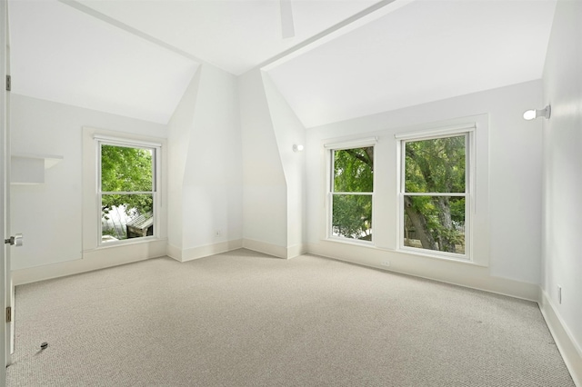 unfurnished room featuring light carpet, vaulted ceiling, and plenty of natural light