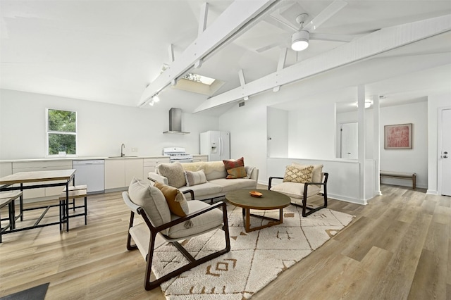 living room featuring lofted ceiling with skylight, sink, ceiling fan, and light hardwood / wood-style flooring