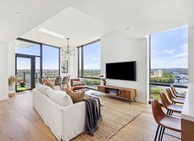 living room featuring a wall of windows, a chandelier, and light hardwood / wood-style floors