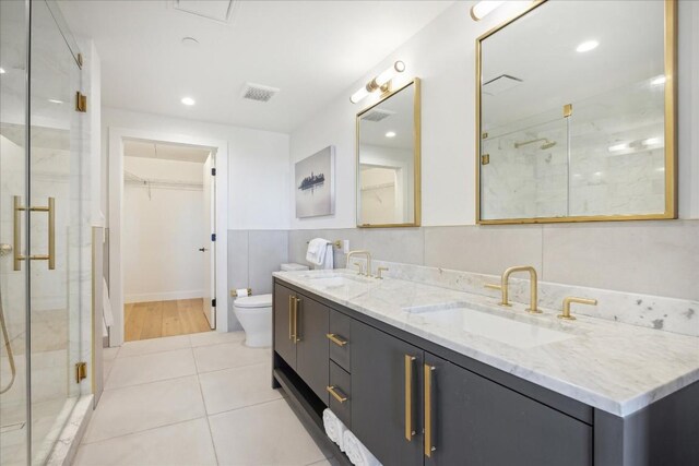 bathroom with vanity, toilet, a shower with shower door, and tile patterned flooring