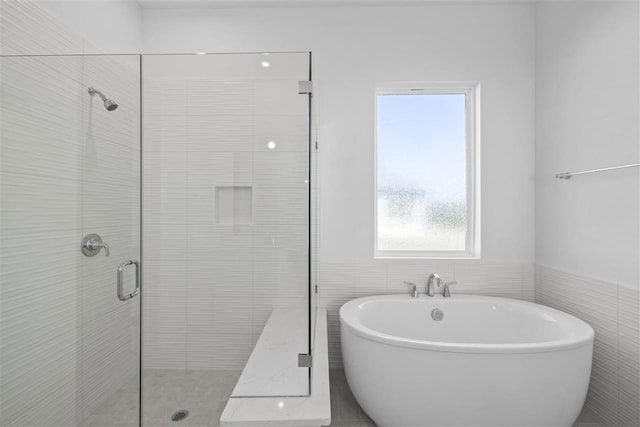 bathroom featuring independent shower and bath and tile walls